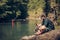 Single male hiker using tablet on nature while sitting on rocky river shore