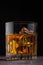 Single malt scotch whiskey in crystal glass with ice cubes on wooden background