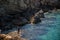 Single man fishing by a river next to massive rocks and cliffs