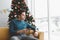 A single man seems lonely using his phone in his living room decorated with Christmas tree