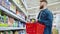 single man is shopping in grocery, buying food in supermarket, taking pack with cereal