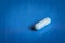 A single medicine white capsule lies on the blue table in close-up