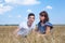 Single mother looking with love at her teen age son, people sitting on wheat field