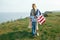 Single mother with son on independence day of USA. Woman and her child walk with the USA flag on the ocean coast