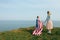 Single mother with son on independence day of USA. Woman and her child walk with the USA flag on the ocean coast