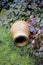 A single, old, vintage and decorative ceramic pot lying on long, uncut green grass in a domestic garden outdoors. Rustic