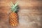 Single one full whole organic pineapple fruit on wooden background ripe fully grown mature, laid down on its side negative empty s