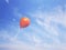 Single orange balloon in the blue sky