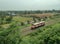 Single orange diesel engine locomotive drives on the railway pass through the rice field