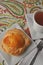 Single person breakfast of sweet pastry with fruit jam and a cup of hot tea on a colorful background