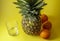 Single pineapple isolated on yellow background with empty glass