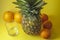Single pineapple isolated on yellow background with empty glass