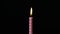 Single pink striped birthday candle on black background.