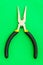 Single pliers tool with rubber handles for the master electrician on green background