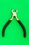 Single pliers tool with rubber handles for the master electrician on green background