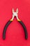 Single pliers tool with rubber handles for the master electrician on red background