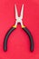 Single pliers tool with rubber handles for the master electrician on red background