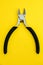 Single pliers tool with rubber handles for the master electrician on yellow background