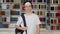 Single portrait of smiling confident male student teenager looking at camera in library