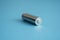 A single rechargeable battery on blue background. Silver alkaline AA battery for different device. Energy.