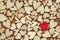Single red heart on background of tiny wooden hearts for love, romance, or Valentine`s Day