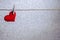 Single red heart hanging from string by clothes peg on silver background. Romantic Valentine`s Day scene with copy space