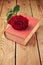 Single red rose flower on book over wooden background
