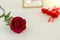 Single red rose, hearts, and card on table