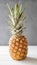 Single ripe illuminated pineapple on a white wooden table and gray background. Juicy standalone ananas.