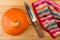 Single ripe pumpkin, kitchen knife and napkin on wooden table