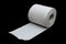 Single roll of unrolled white toilet paper. Isolated on black background. Close-up