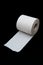 Single roll of unrolled white toilet paper. Isolated on black background. Close-up