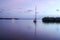 Single sailboat in the calm sea during light purple twilight