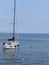 Single sailboat lies at anchor in a harbor waiting for the wind to shift . Tuscany, Italy