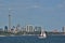 Single sailboat with red rimmed jib sunny Toronto skyline late afternoon