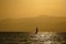 A single sailboat sailing in the ocean at sunset