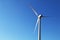 Single shining white wind turbine bright blue sky