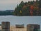 Single silver canoe standing on wood dock next to lake with colorful fall forest behind in Algonquin Park, Canada