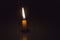 Single simply candle lighted in the dark background