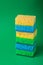 Single stack of sponges in blue, green, yellow colors on green paper background