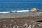 Single straw parasol on black sand beach