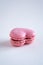 A single strawberry flavoured heart-shaped French macaron, copy space on neutral background