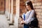 Single student walking and reading mobile phone messages with a university building in the background