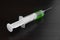 Single Syringe With Green Liquid On The Black Wood Background