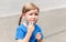 Single tired, unhappy and worried anxious little girl, child taking off a protective face mask, young school kid portrait. Covid19