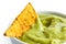 Single tortilla chip in bowl of guacamole.