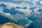 A single traveler with a backpack stands on a cliff of huge mountains