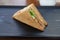 A single Tuna sandwich on black serving plate. One Club Sandwich with chicken, ham, cheese, tomatoes, cucumber, bacon, lettuce,