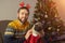 Single unmarried man with his pug dog is sitting near Christmas tree at home. Celebrate Christmas with your lovely pet