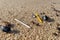 Single use plastics - plastic straws washed up on a sandy beach, with sea shells.